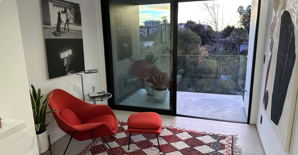 Living room with a red lounge chair and floor-to-ceiling glass