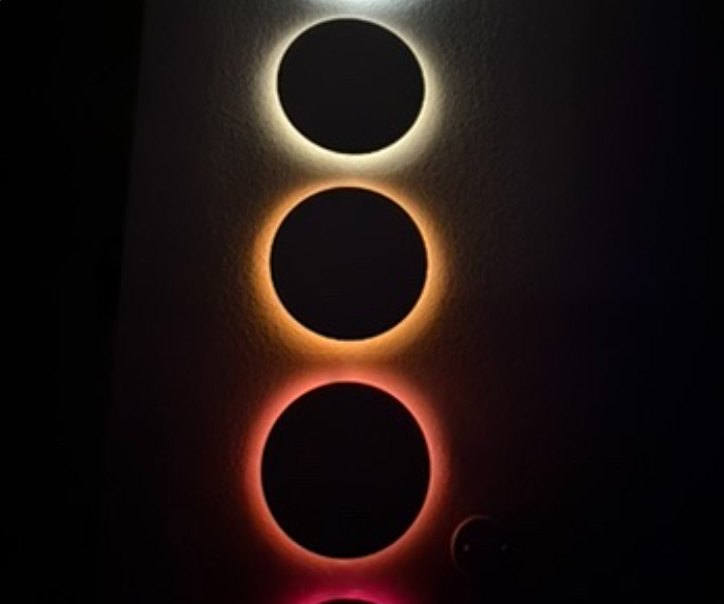 Three circular recesses glowing from cool white to warm amber
